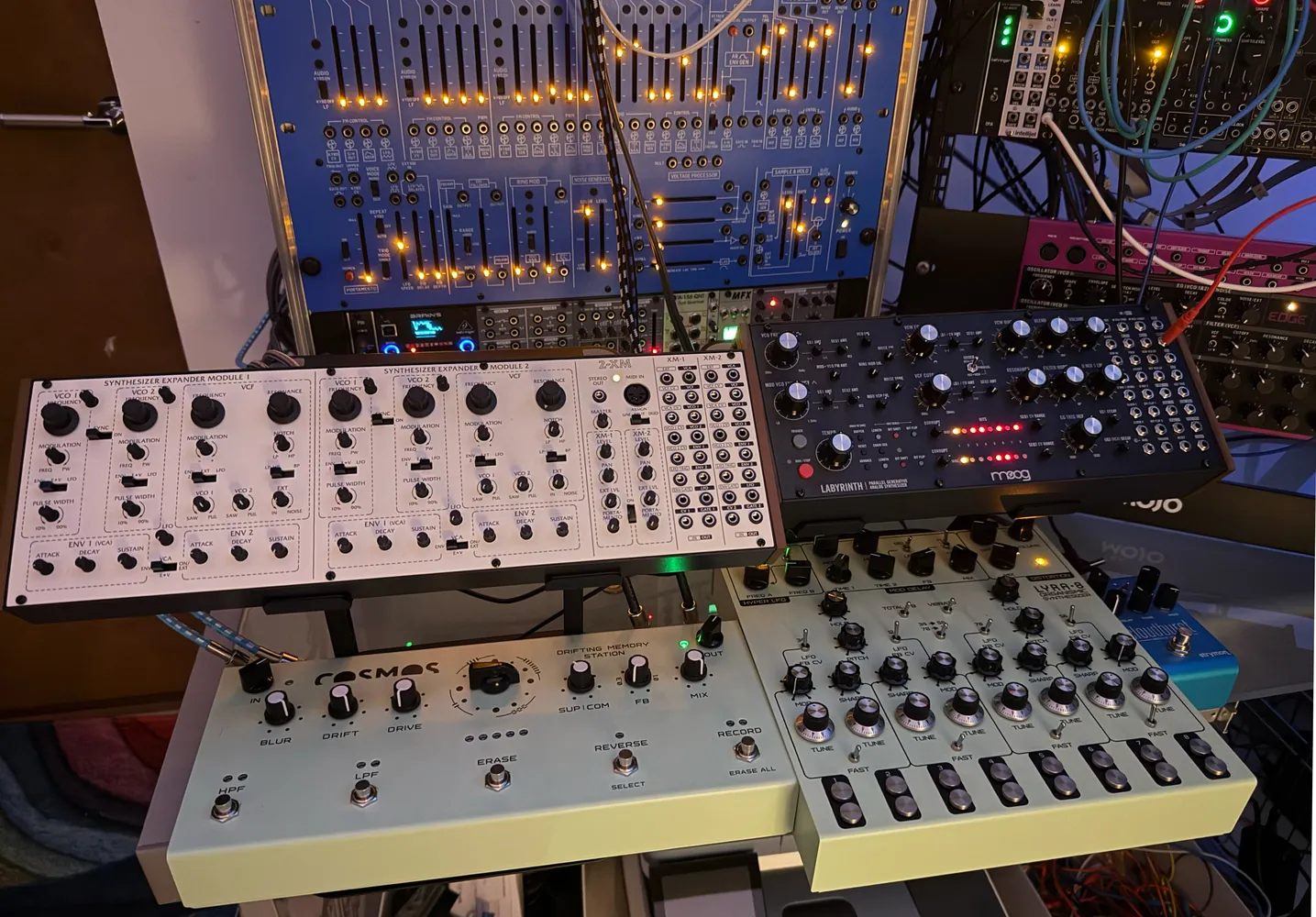 Cream and black desktop synthesisers in front of the blue modular panel.