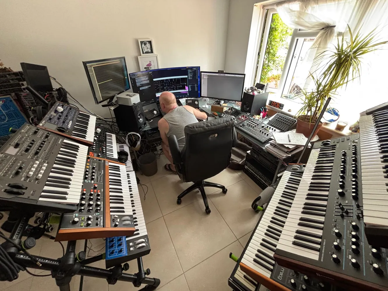 Chris at the desk with NeuralDream on the screens, surrounded by keyboards and synthesisers.